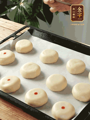 收口向下放在案板上，輕輕將月餅坯按扁，用筷子點紅點做裝飾